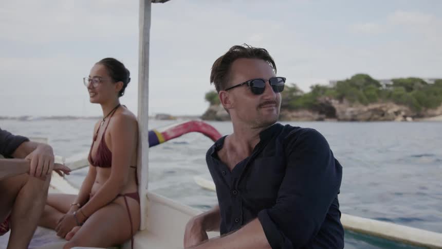 Two men and a woman ride in a boat