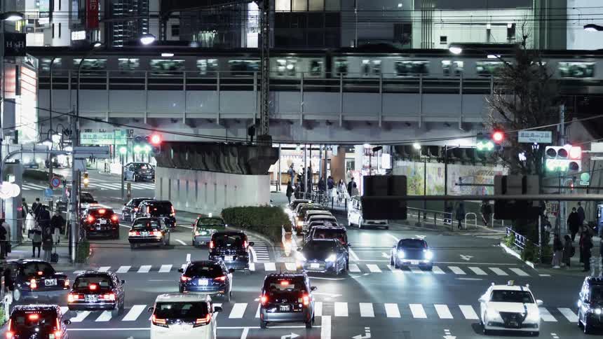 Cars drive on urban highway as train passes overhead