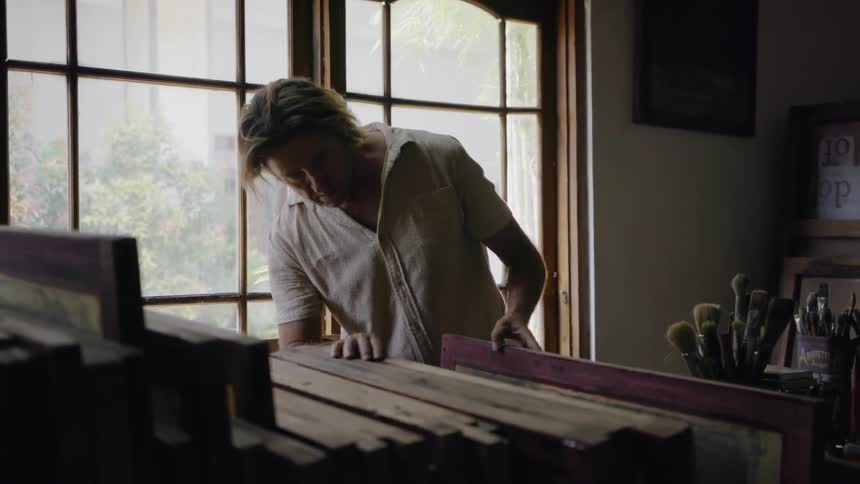 Man looks through a stack of canvases in an art studio