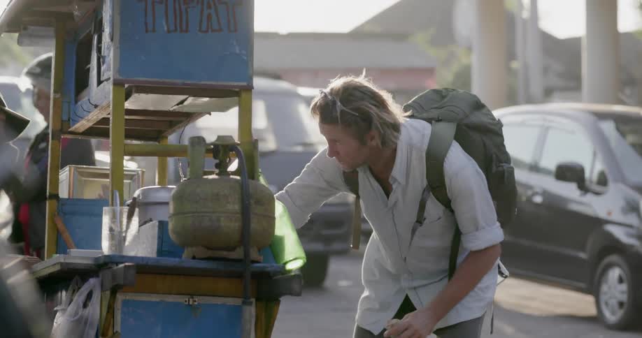 The man buys some food from a street vendor