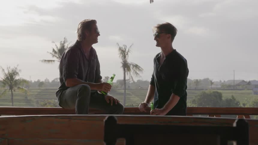 Two men drink beer on a patio