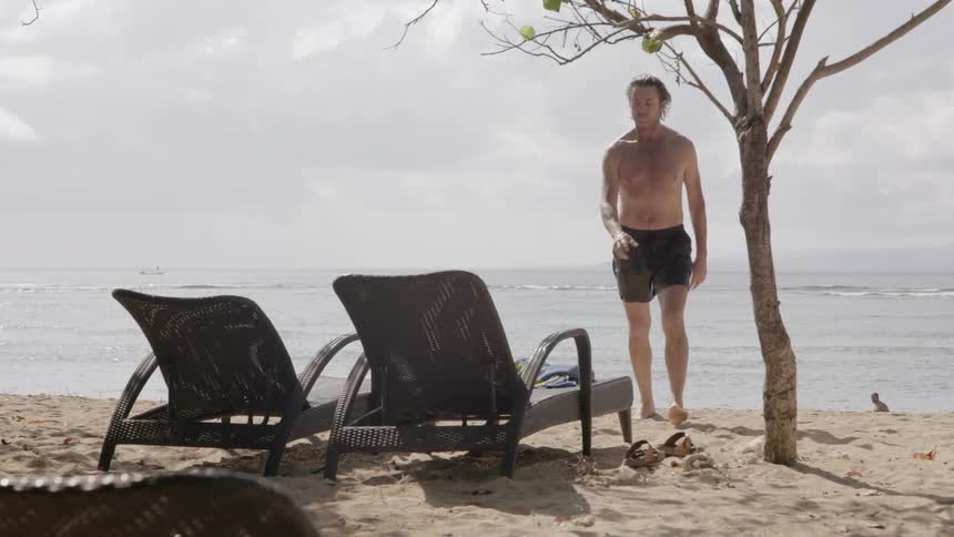 A man grabs a towel to dry off on the beach
