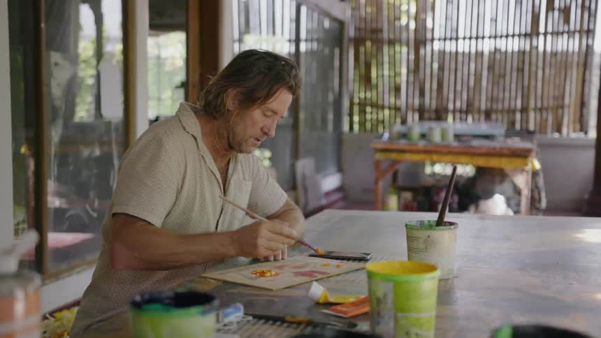 Man paints and taps on his phone