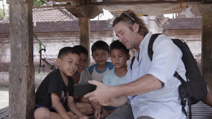 A man shows a group of children his phone