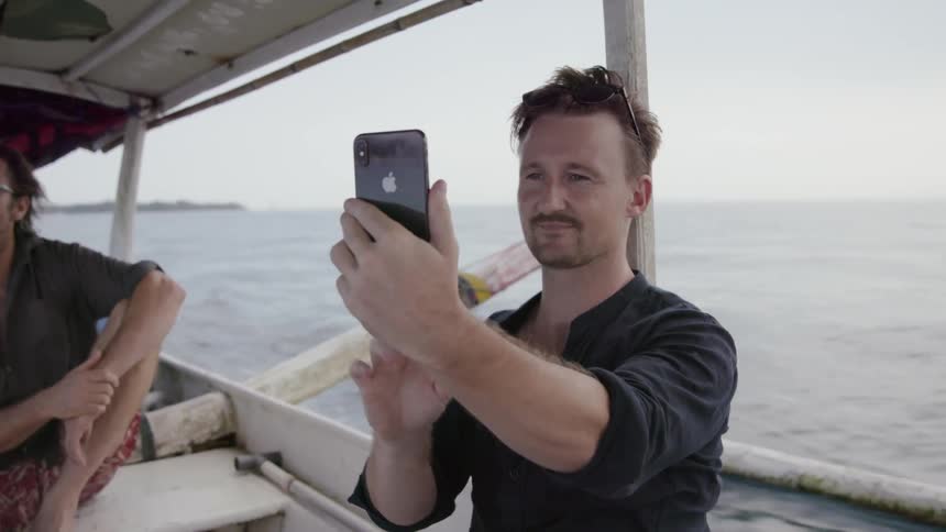 A man takes a selfie from a boat
