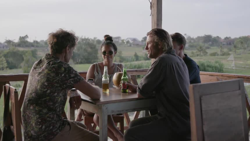 People sit outside at table talking and drinking beer