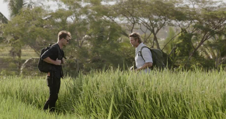 A man takes a photograph of a man in a field