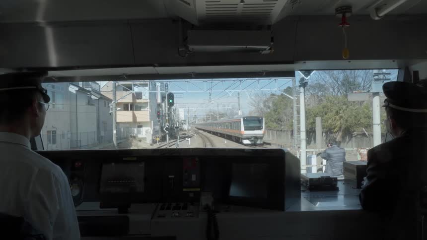 Two men in a train watch as another train passes by