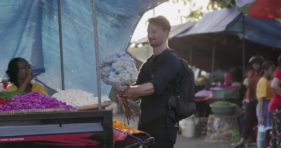 A man purchases flowers from a street vendor