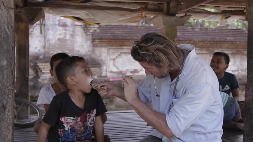Male doctor checks the throat of a young boy