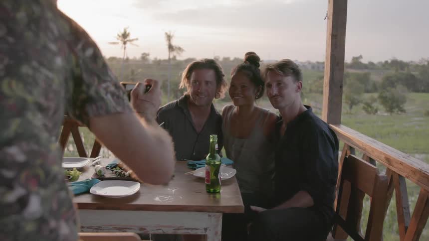 Friends pose for a photograph on a patio at sunset