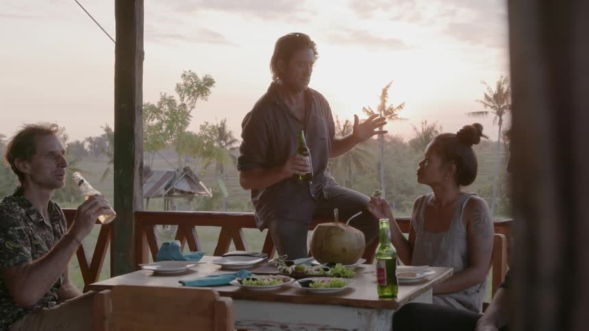 Friends drink and eat on a patio at sunset