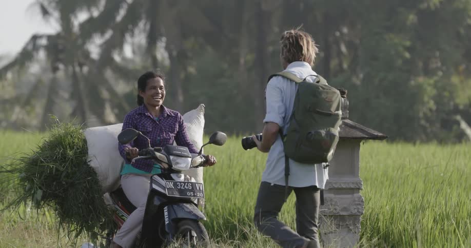 A man photographs a woman on a scooter