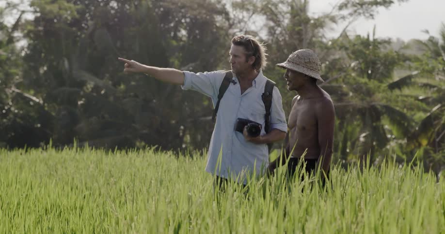 A photographer talks to a man in a grassy field