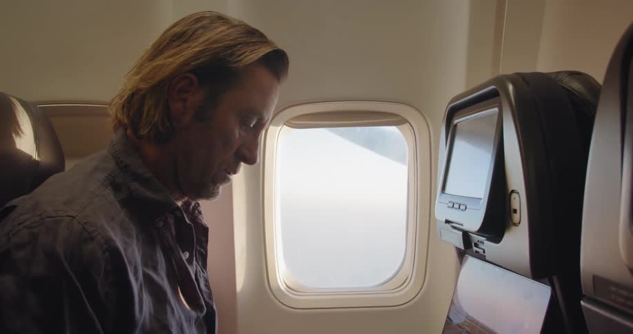 Man types on a laptop in an airplane