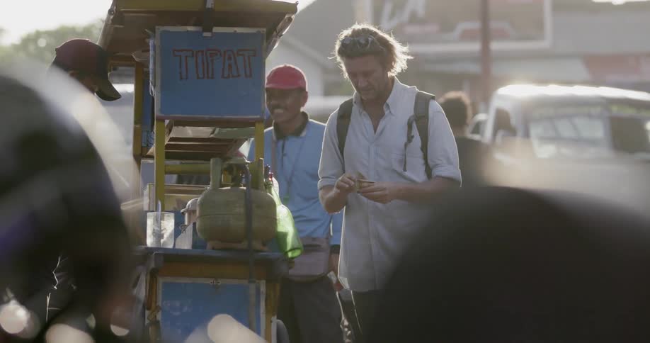 A man is making a deal with a street vendor outside in daylight