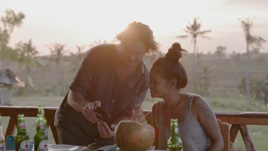 A man shows a woman something on his phone on the deck
