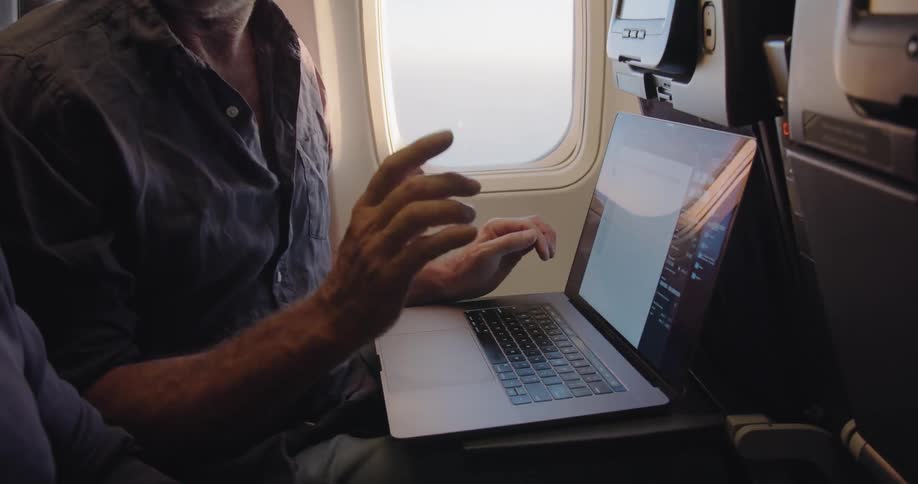Man works on a laptop during a flight