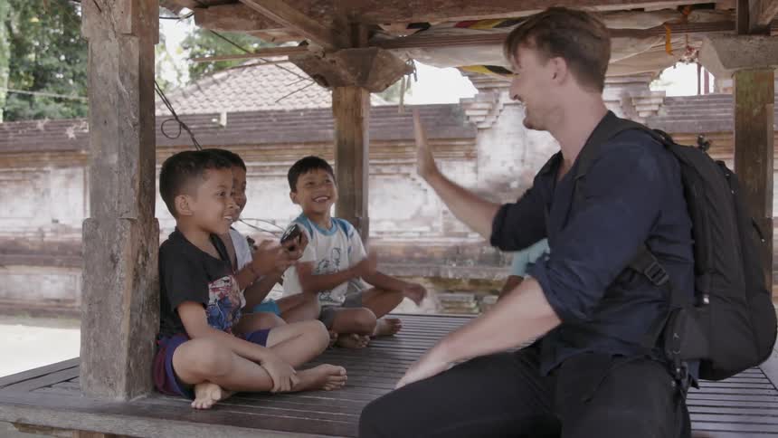 A man high fives young boys in a village