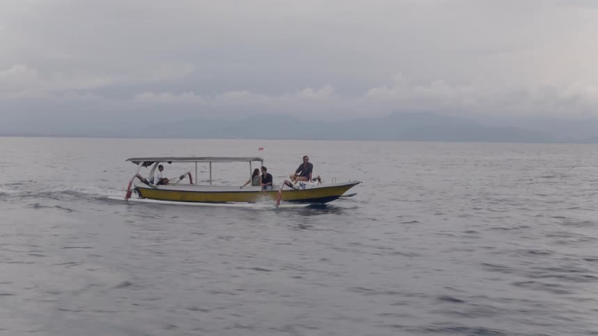 People sit on a boat moving through the ocean