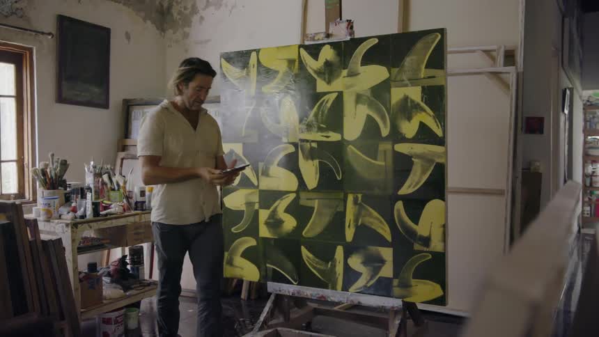 A man is taking a photo of a piece of artwork inside in daylight