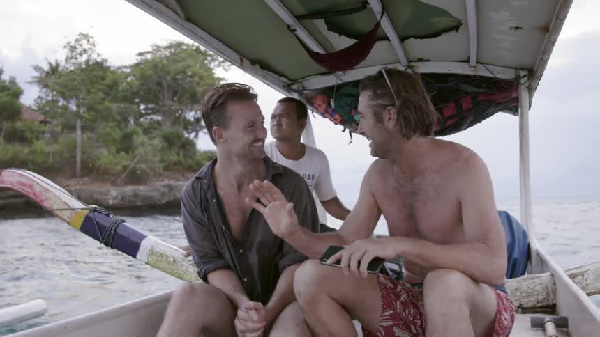 Two men are riding on a boat as it speeds across the ocean on a cloudy day