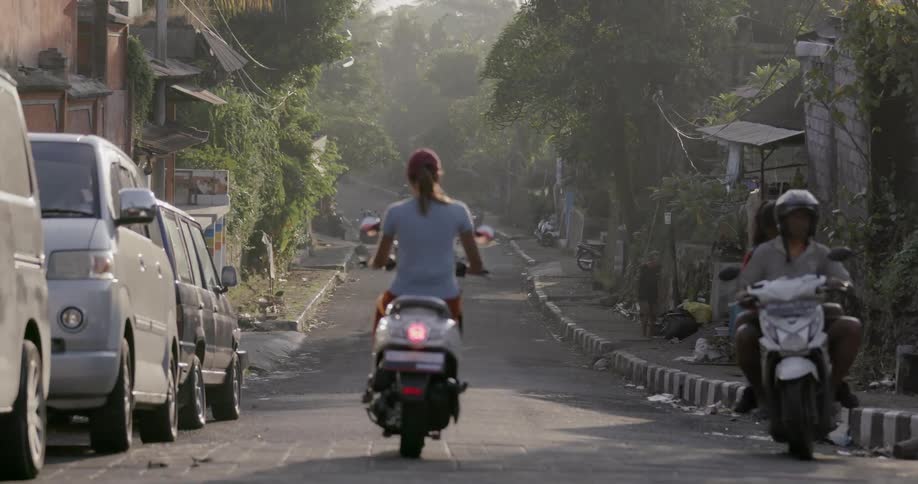 The people travel down the road on scooters and vehicles
