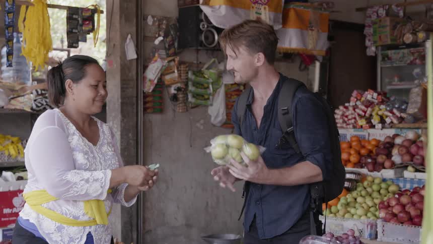 Man gives a woman money for a bag of produce at a market