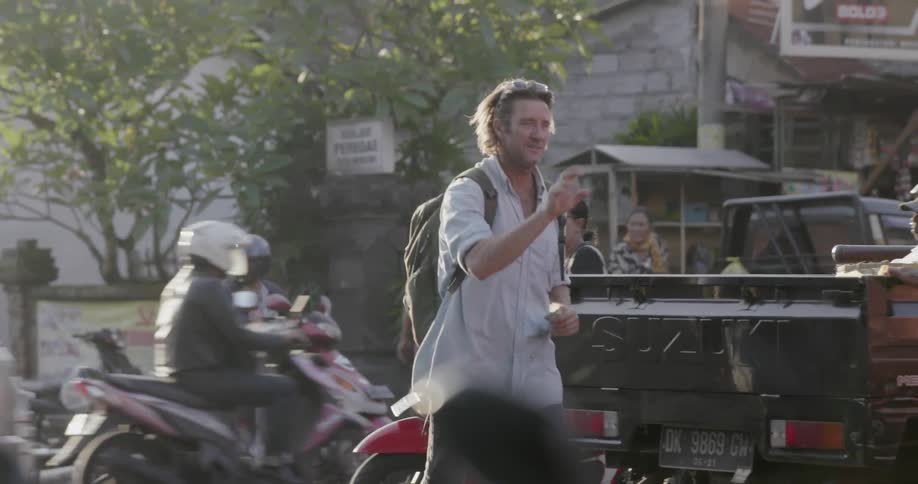Man waves to pedestrians and commuters in a city