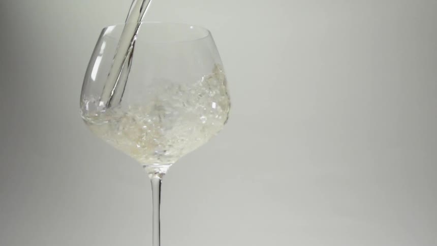 White liquid pours into a wine glass