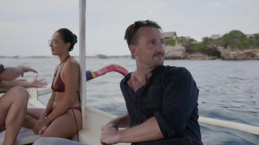 Two men and a woman ride in a boat