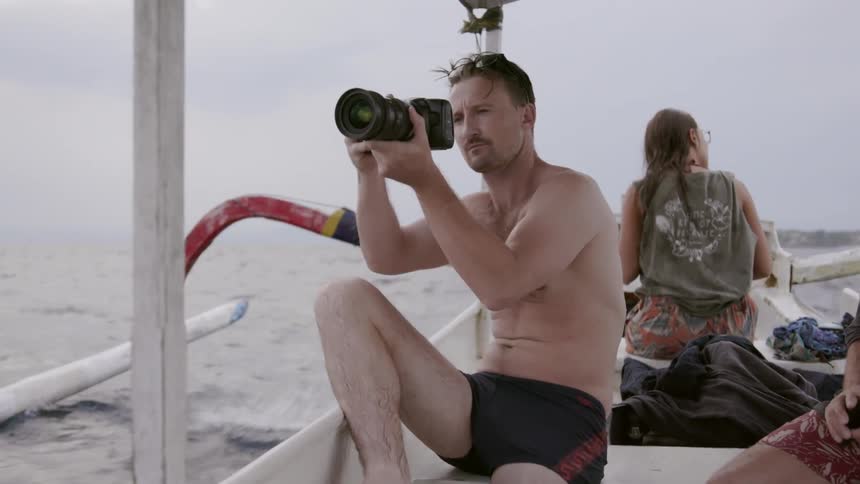 A man takes photos from a moving boat