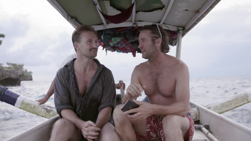 Two men talk as they travel on a boat