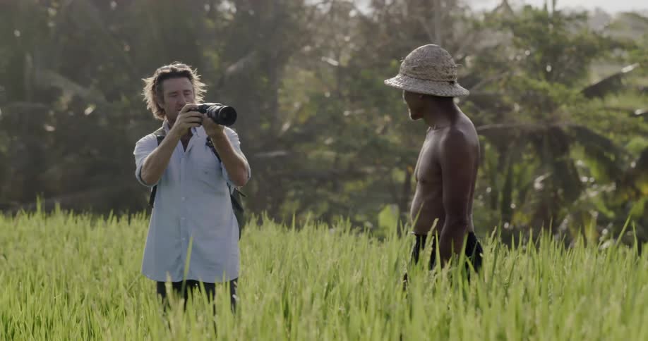 Photographer takes a photo of a man in a grassy field