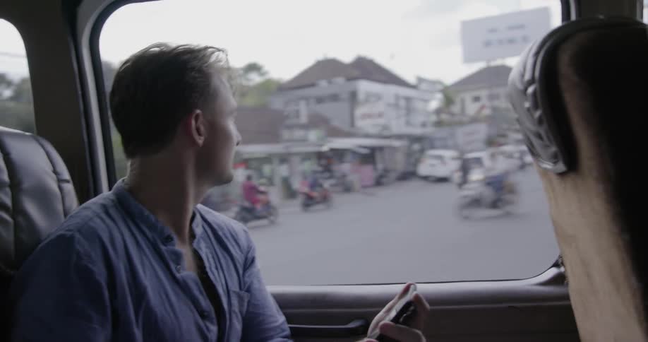 Man uses his phone while riding on a bus