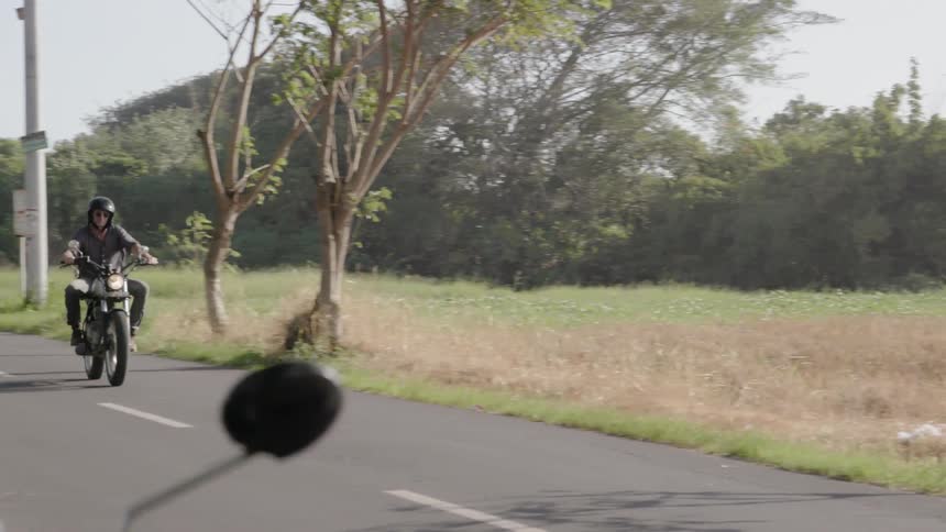 A motorcyclist rides on a rural road