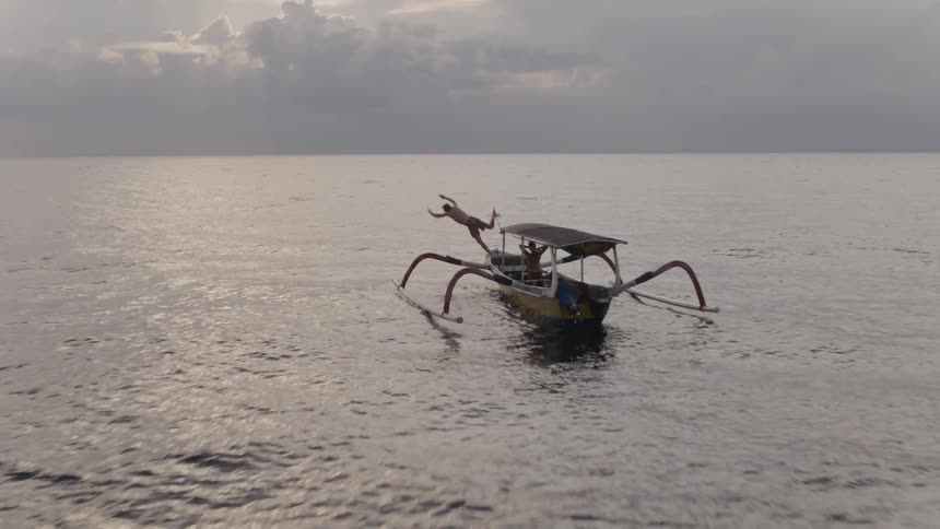 A man jumps from a boat to swim in ocean water