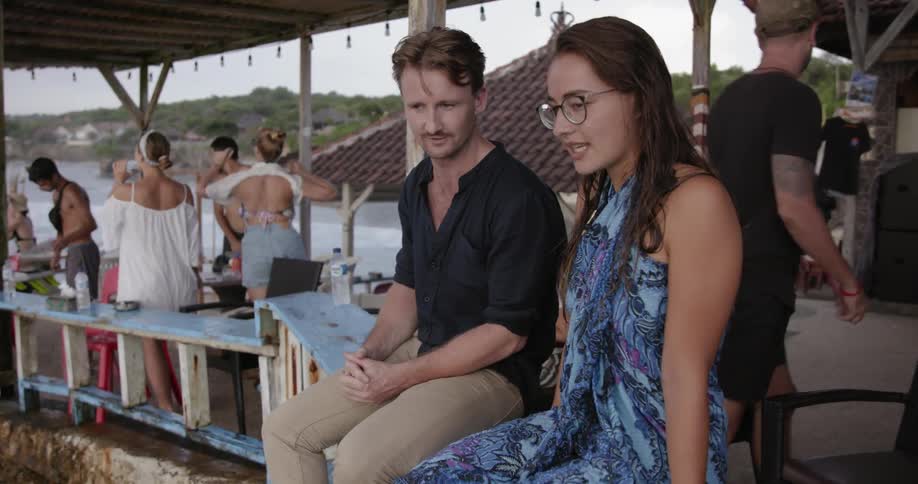 A man and woman talk on a beach patio