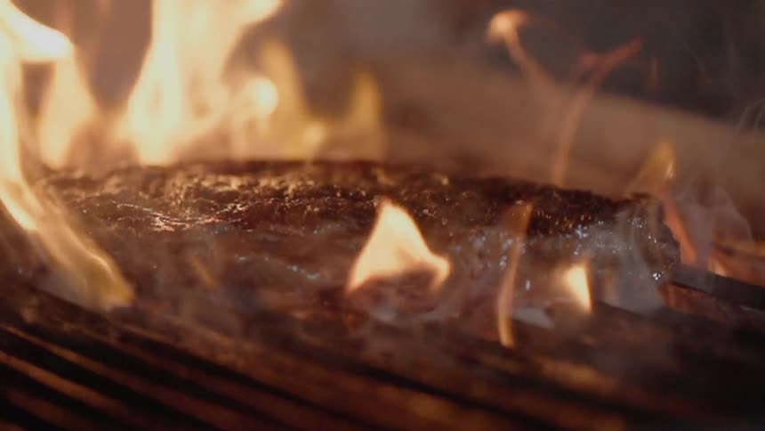 The steak is flipped on the grill