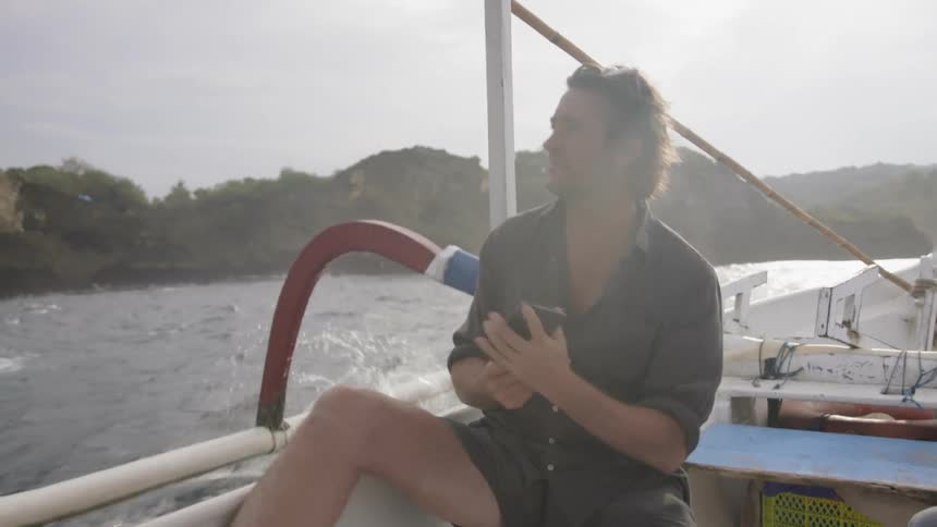 A man takes a photo while riding in a boat