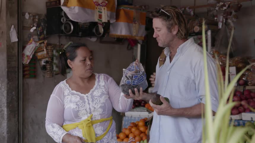 Woman hands a bag of produce to a man at the market