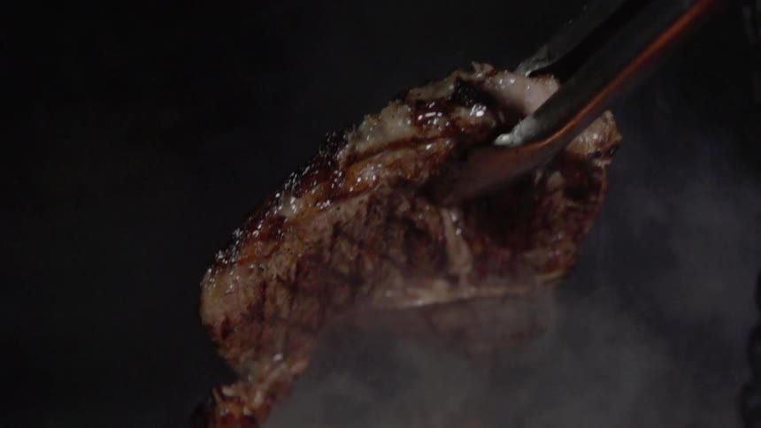 The cooked steak is removed from the grill