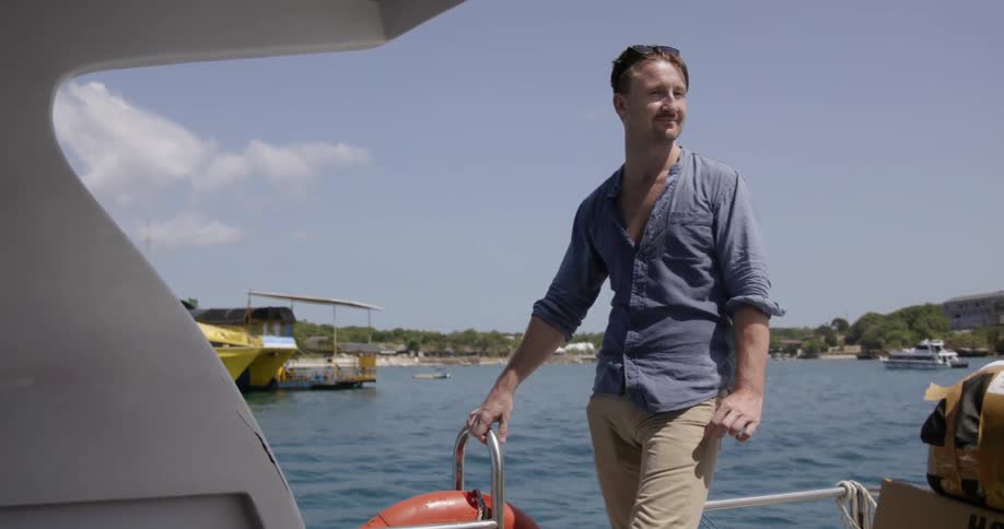 The man looks around on the boat smiling