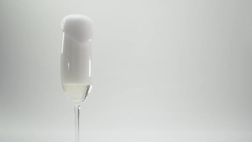Foam spills out over a glass of liquid