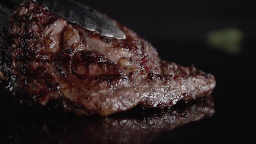 Cooked steak is lowered with tongs