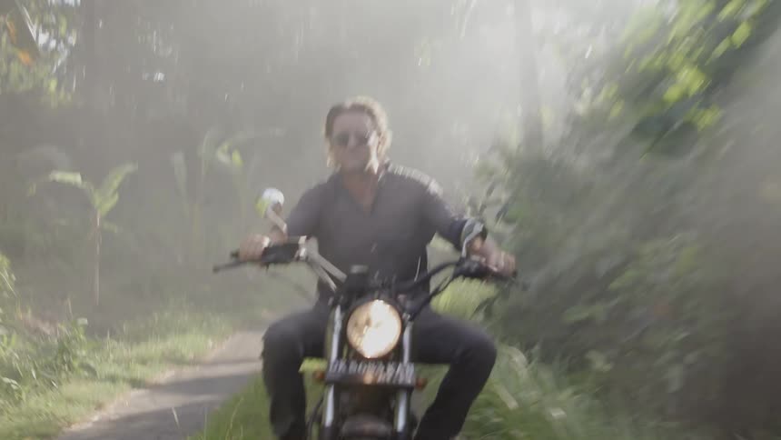 A man rides a motorcycle through a path in the woods