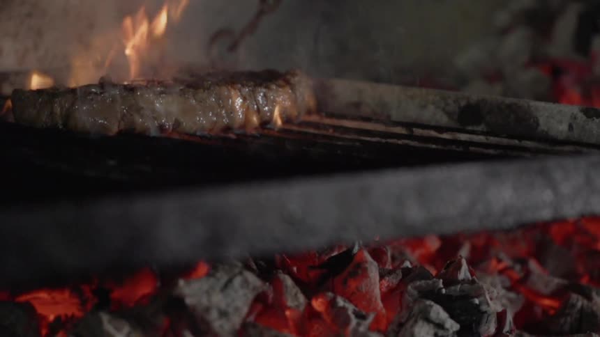 Meat cooks on a grill over the coals