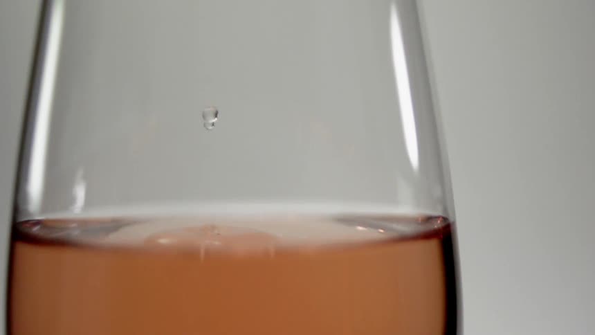 A drop of wine splashes in a wine glasses