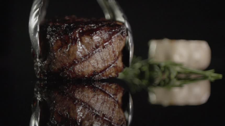 A piece of cooked meat is dropped using tongs