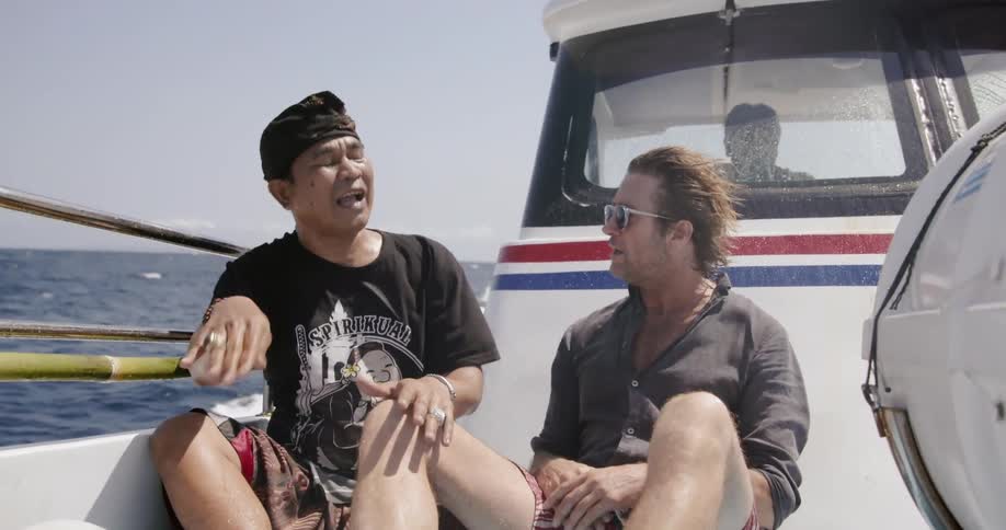 Two men are having a discussion as they ride on a boat in daylight